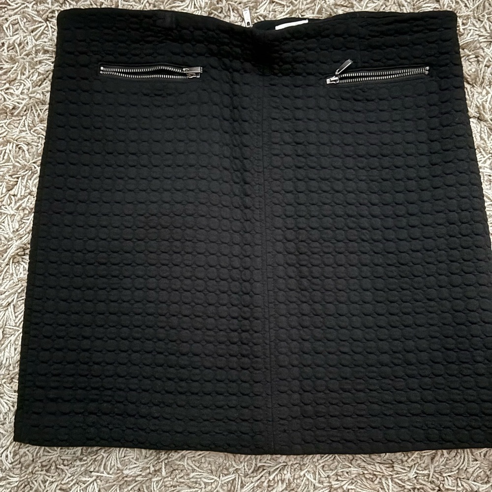 Sharp quilted, soft stretchy black mini skirt. Two silver zipper pockets front